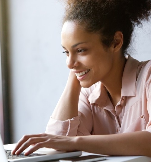 Woman behind laptop looking at Academy Online